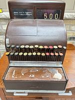 Front view showing keys, price display, wood drawer front, overall wear