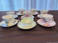 Group shot of all eight teacup and saucer sets displayed on table