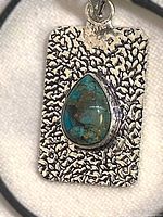 Front view of textured silver pendant with chrysocolla cabochon
