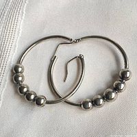 both sterling silver hoop earrings laid flat showing bead accents
