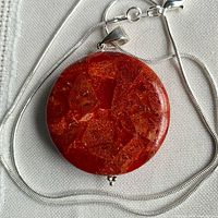 Front view of round red coral pendant on sterling snake chain