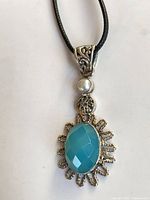 Front view of pendant showing chalcedony, faux pearl, silver detailing, and cord