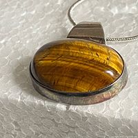 close-up of pendant front showing tiger eye stone and silver bezel