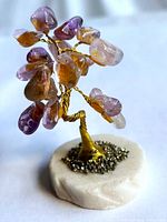 Front view of brass wire tree with amethyst leaves on white base