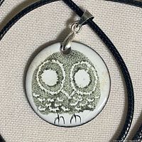 Front view of enameled owl pendant on cord