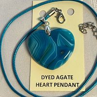 Front view of heart-shaped dyed agate pendant on blue cord necklace with clasp and extender
