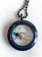 Front view of locket showing skull charm and rhinestones inside black frame