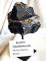 Full view of black tourmaline specimen on stand with label