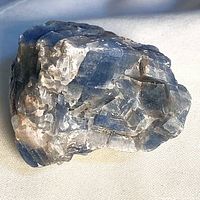 Rough blue calcite crystal showing blue coloration and white veining