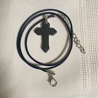 Full view of hematine cross pendant on cord with clasp