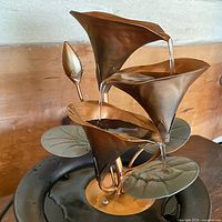 Front view showing three copper lily cups, bud, leaves and water flow