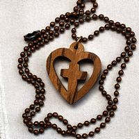 Full view of wooden heart-shaped pendant with cross cut-out on bead chain