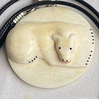 Front view of circular pendant showing polar bear carving and black cord