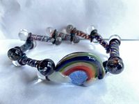 Full view of glass bracelet showing rainbow focal and bead arrangement