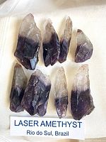 Seven to eight amethyst laser crystals laid out on fabric