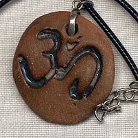 Front view of clay pendant showing OHM symbol detail