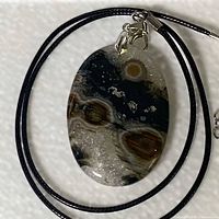 Front view of ocean jasper pendant on black cord