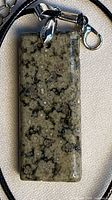 Front view of polished ocean jasper rectangular pendant on cord