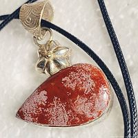 Pendant showing red jasper stone, floral accent and bail on black cord