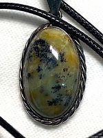 Close-up of dendritic agate cabochon in silver tone bezel on black cord