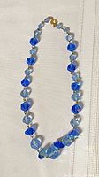 Full view of necklace laid flat showing bead shapes, colors and clasp