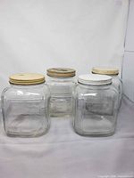 Group shot of four square glass canisters with lids