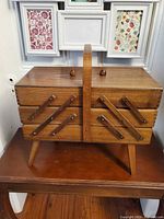 Overall view of wooden accordion sewing box on legs, handle visible