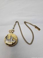 Closed pocket watch with attached chain showing fisherman relief