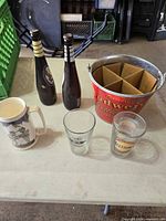 Overall lot on table showing bucket, bottles, glasses, stein