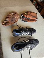 Adidas cleats, Franklin glove, Wilson glove on table