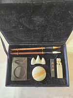 Open calligraphy box showing brushes, inkstone, brush rest, water dish, ink stick and seal