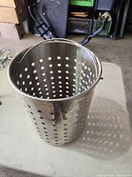 Side view of perforated stainless steel basket showing cylindrical form and side lift bracket