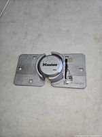 Master Lock hidden-shackle padlock mounted between two aluminum plates with key inserted