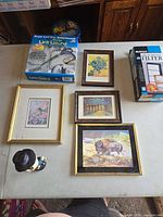 Table with boxed Lint Lizard, framed prints, dog figurine and Holmes filter box