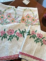 Top view of all four embroidered linens showing floral designs and lace trim