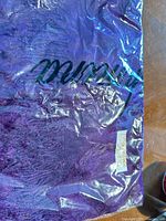 Purple pashmina scarf/shawl in clear packaging with script logo visible