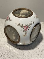 Overall view showing porcelain cube with brass-rimmed photo windows and floral design