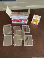 Closed cardboard box printed "Hockey", six empty clear plastic hinged card boxes, one small case with Rookie Checklist label