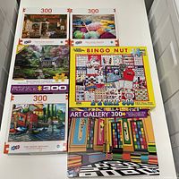 Fronts of five boxed 300-piece puzzles laid out on table