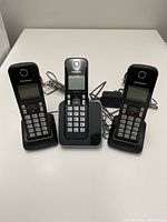 Front view of three Panasonic cordless handsets on their respective bases with cords