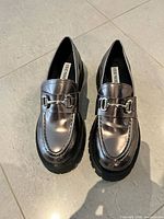 Top view of both metallic loafers showing color, hardware, and insole branding