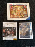 Three boxed 1000-piece puzzles: Ravensburger collage, Aquarius Harry Potter Diagon Alley, tall ship HS-905