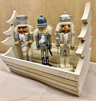 Three nutcracker figures displayed in wooden crate
