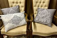 All three embroidered pillows displayed on chairs