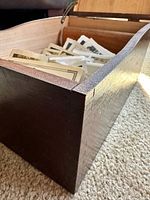 Dark-stained wooden box corner showing dovetail joints and interior with loose photographs