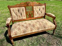 Front view of settee showing overall design, carved crest, turned legs, floral upholstery