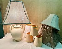 group shot of ceramic lamp with attached square shade and six additional shades