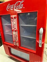 Front view showing Coca-Cola logo, clear panels, selection buttons, lower display window
