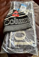 Hat and scarf set in sealed plastic packaging showing tags