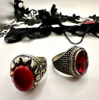 Two silver-tone rings with red stones, lace chokers in background